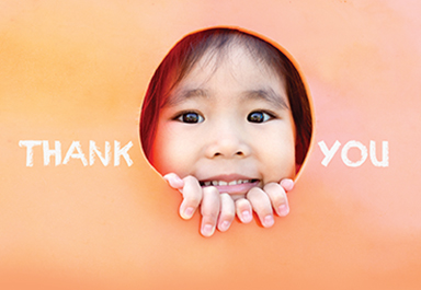 Young girl peeking through a thank you sign