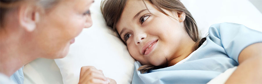 Young girl in hospital bed looking at nurse